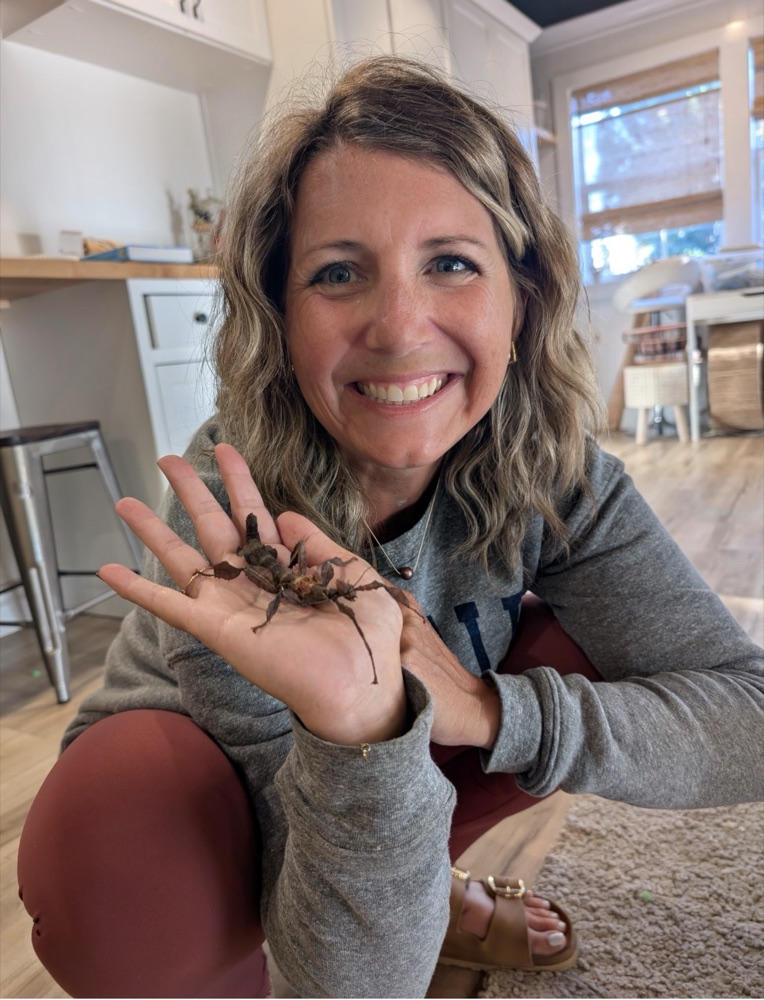 Kara smiling with a stick insect on her palm